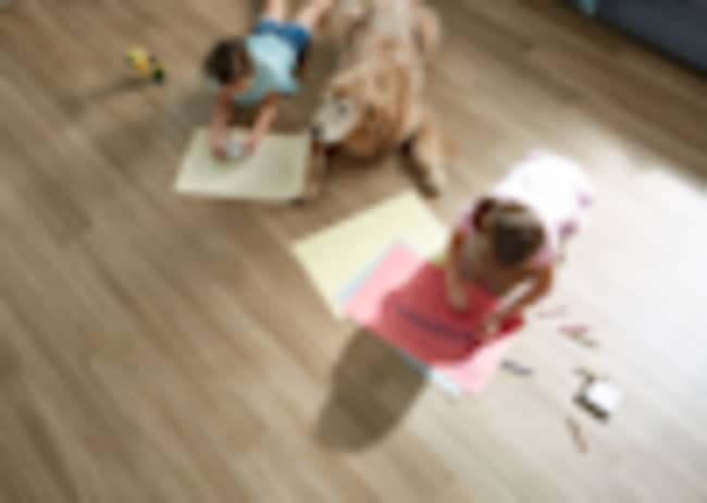 two kids coloring on a hard floor with their dog