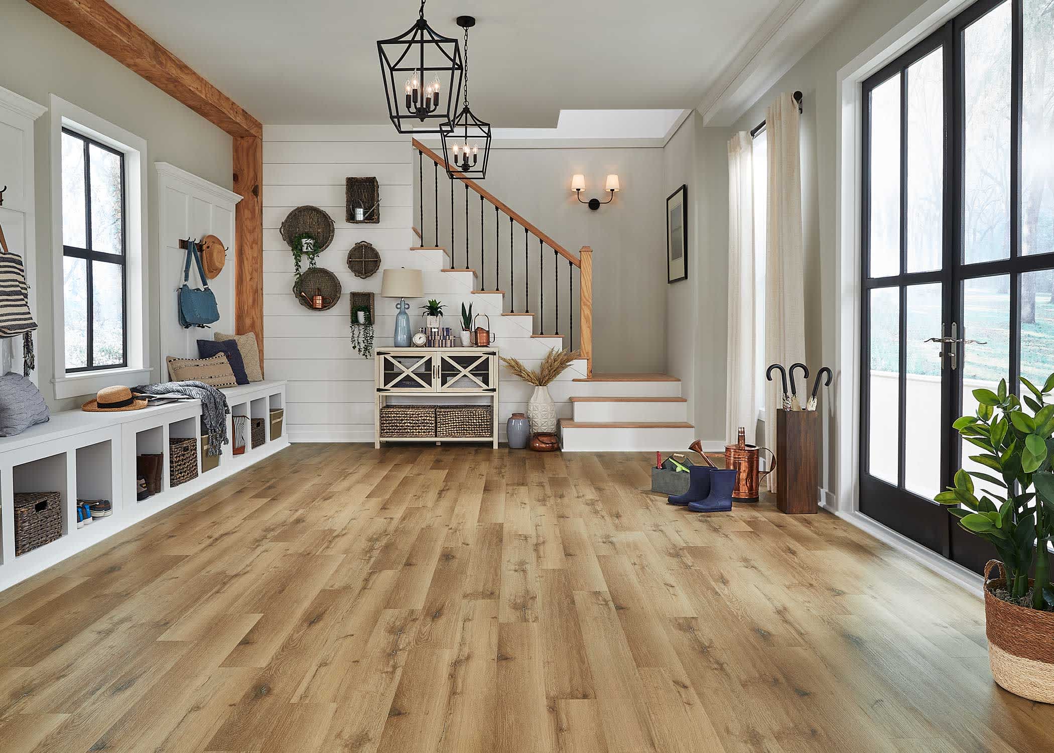 multi-toned brown waterproof rigid vinyl plank flooring in entryway with black pendant lights plus black double front doors with umbrella storage and matching stairs leading to main level