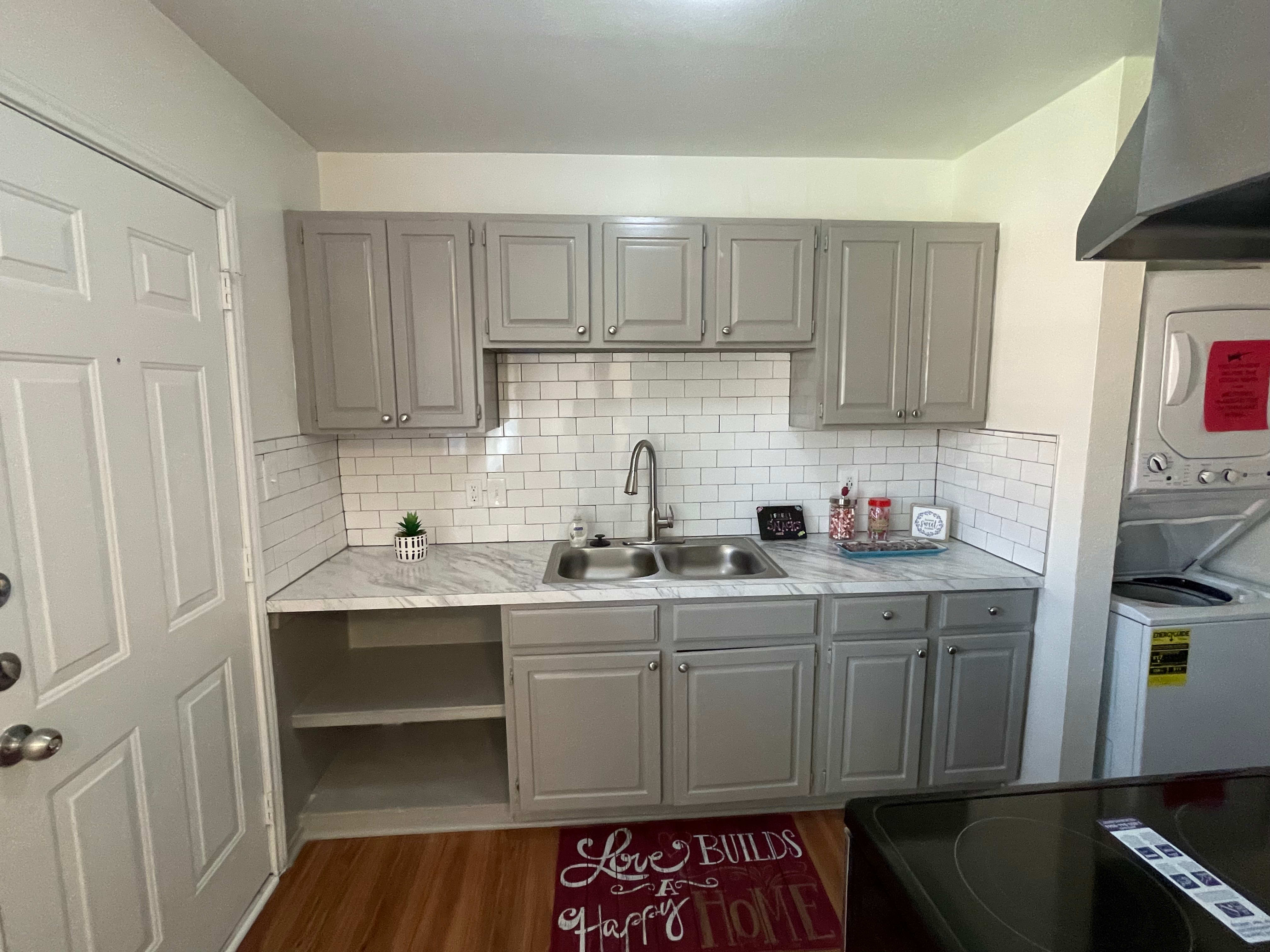 kitchen with gray cabinets and white tile backsplash after renovation