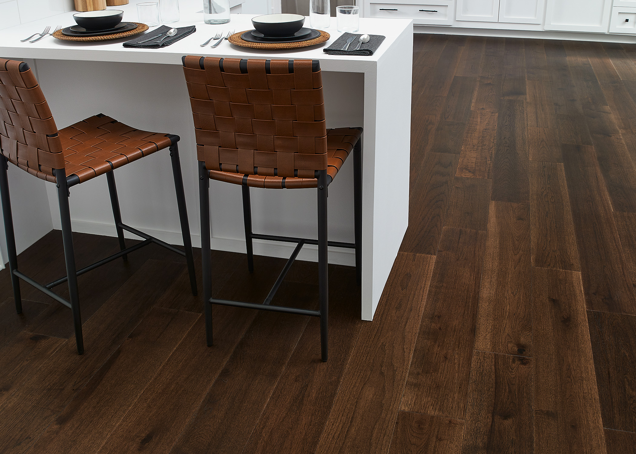 7mm+Pad x 7.48 in Lake Superior Hickory Water-resistant Engineered Hardwood Flooring in kitchen with white cabinets and countertops plus brown leather breakfast stools