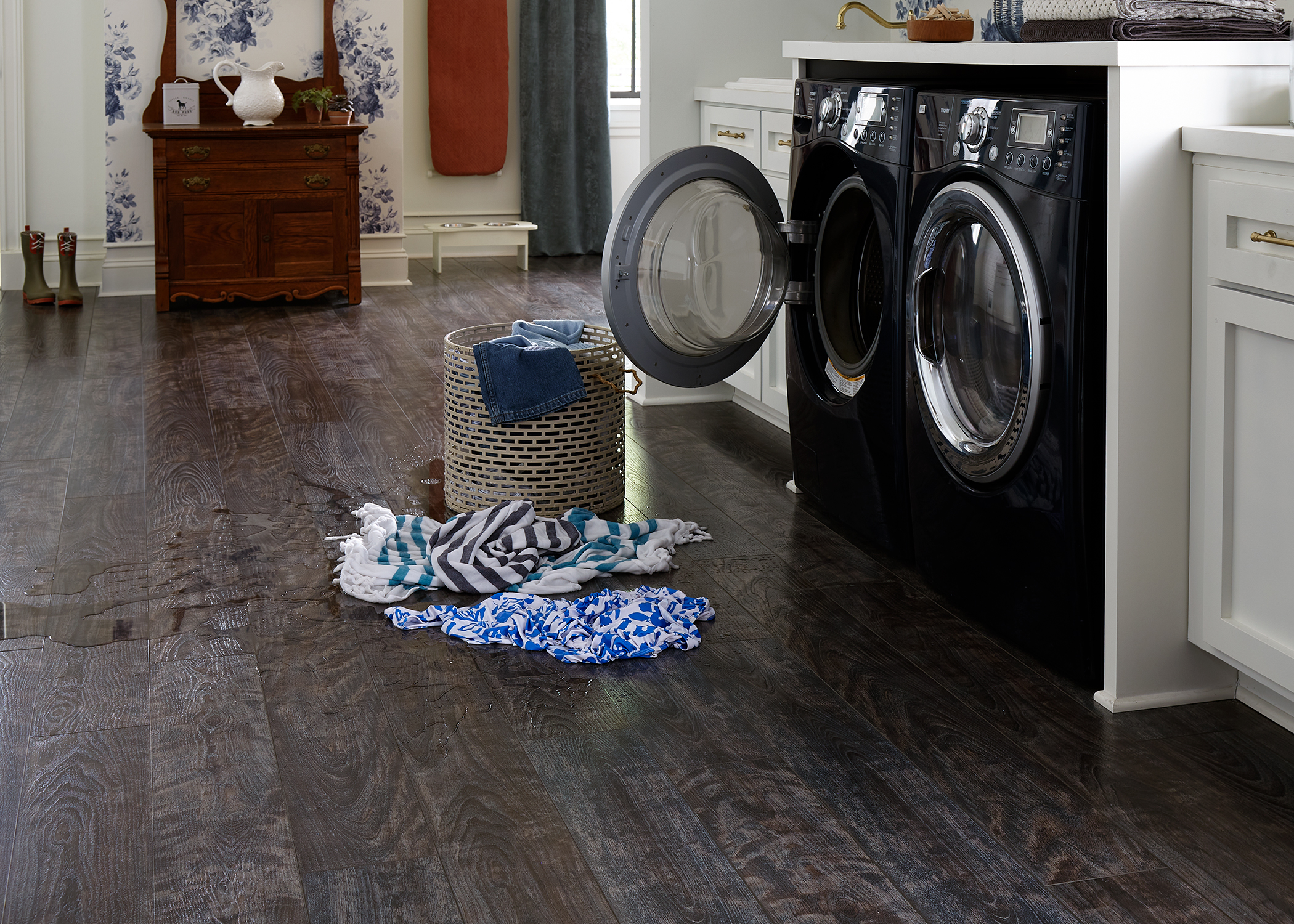 wet clothes on floor of laundry room with rigid vinyl plank flooring