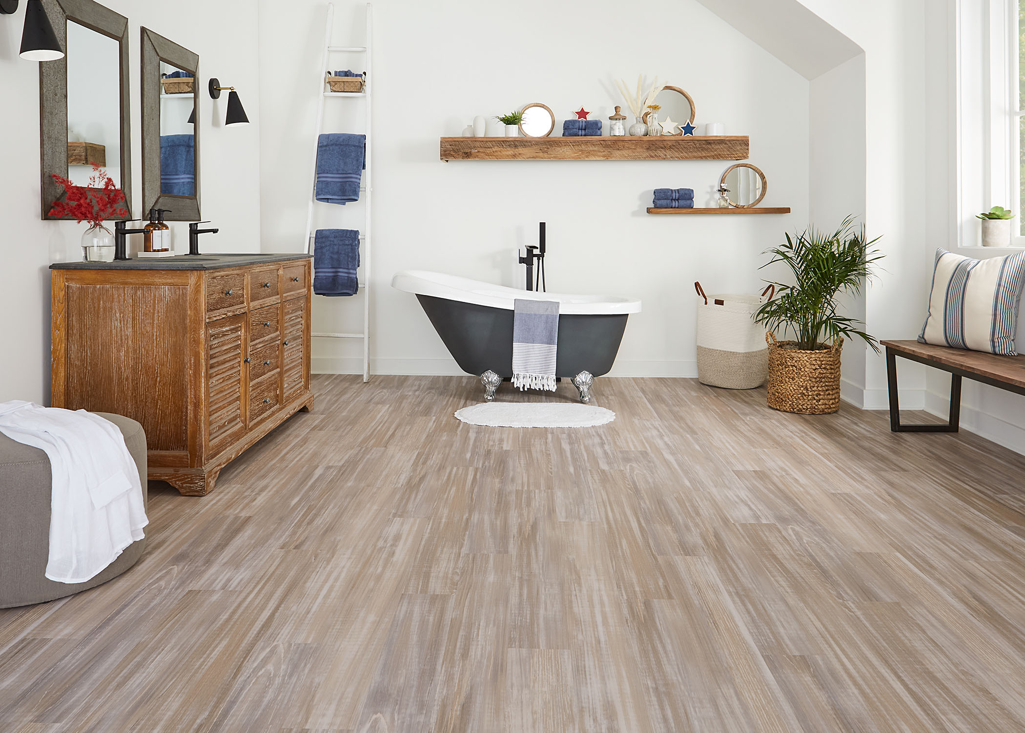 multi toned taupe waterproof rigid vinyl plank floor in bathroom with black and white clawfoot tub plus floating wood shelves and wood double vanity