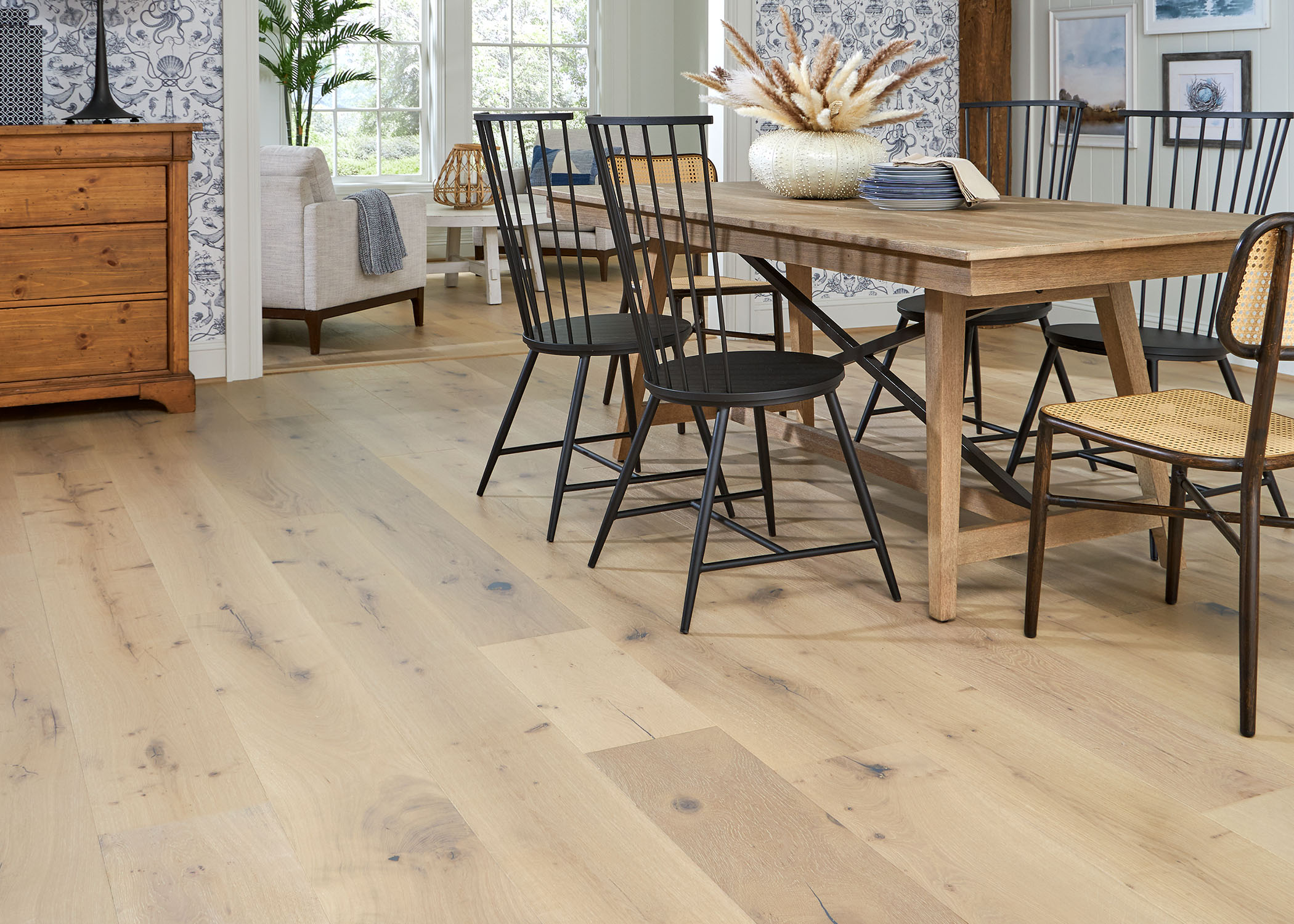 blonde distressed engineered hardwood flooring in dining room with blonde wood dining table and black spindle chairs plus blue and white wallpaper