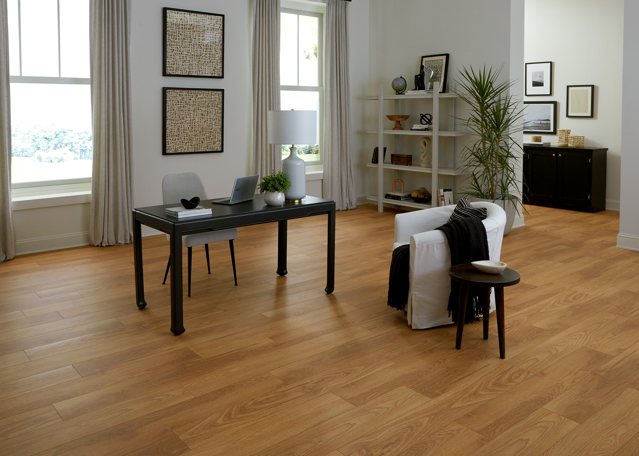 reddish brown waterproof hybrid resilient flooring in office with black desk plus upholstered desk chair and upholstered barrel accent chair next to black side table