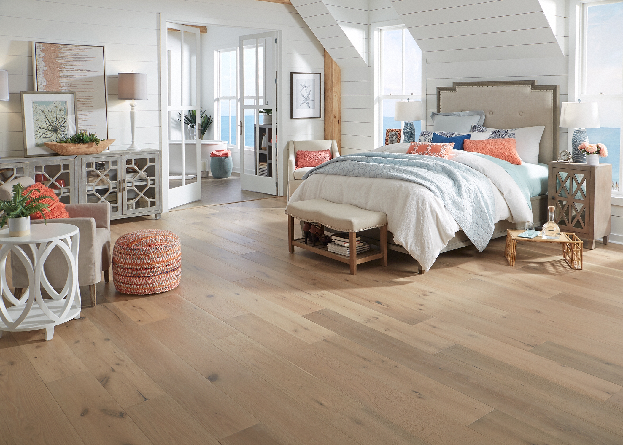 medium blonde distressed engineered hardwood flooring in bedroom with beige headboard and pale green and orange bedding plus white furniture and shiplap on walls