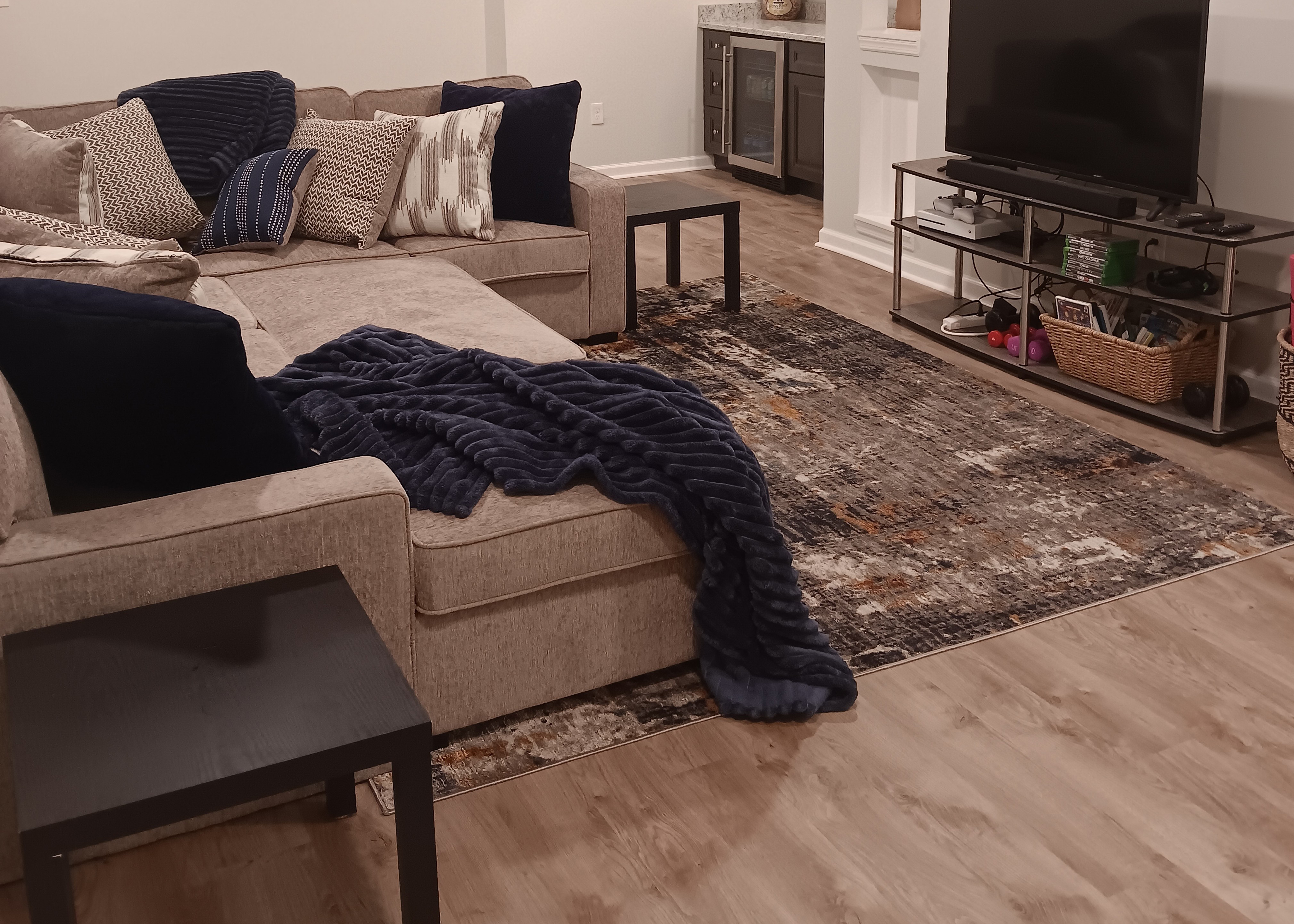 light beige waterproof vinyl plank flooring in lower level with sectional sofa and small area rug