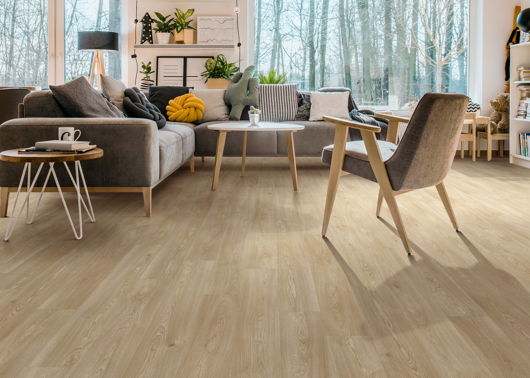 blonde waterproof vinyl plank flooring in living room with dark brown sectional with blonde wood accent table and accent chair