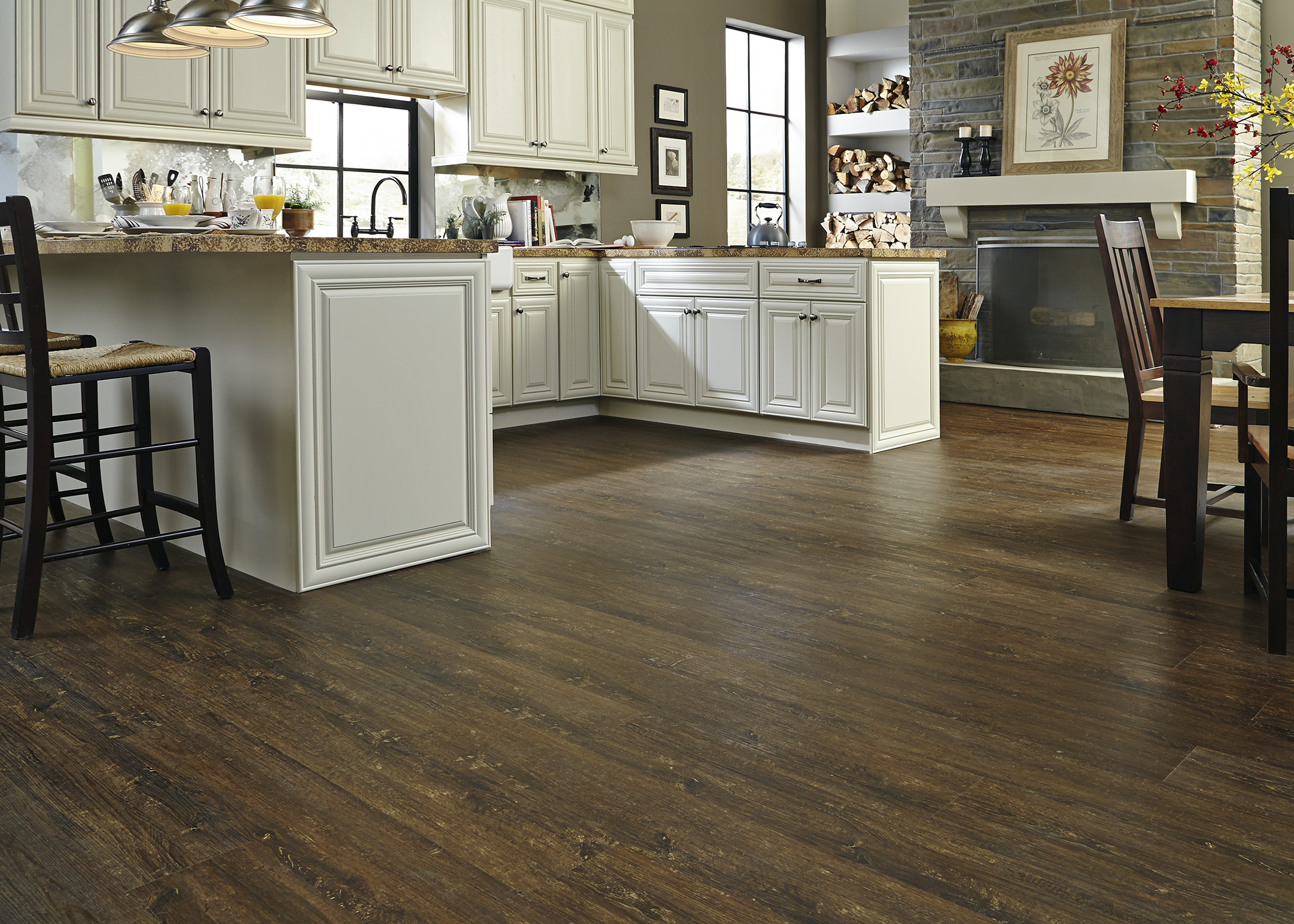 dark brown waterproof vinyl plank flooring in kitchen with off white cabinets and dark brown countertops plus brick fireplace and dining area