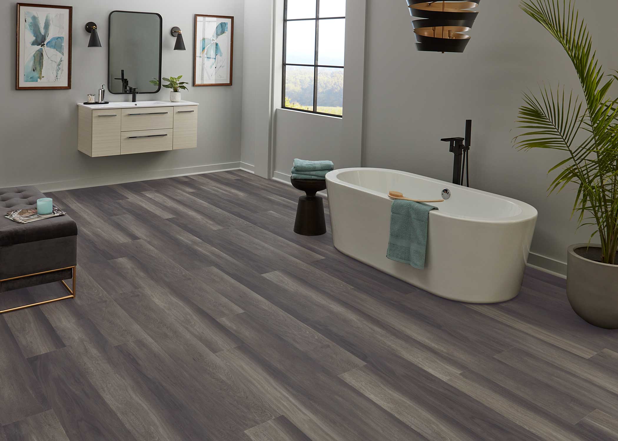 multi toned gray waterproof rigid vinyl plank flooring in bathroom with oval freestanding tub and black fixtures plus gray walls and black chandelier