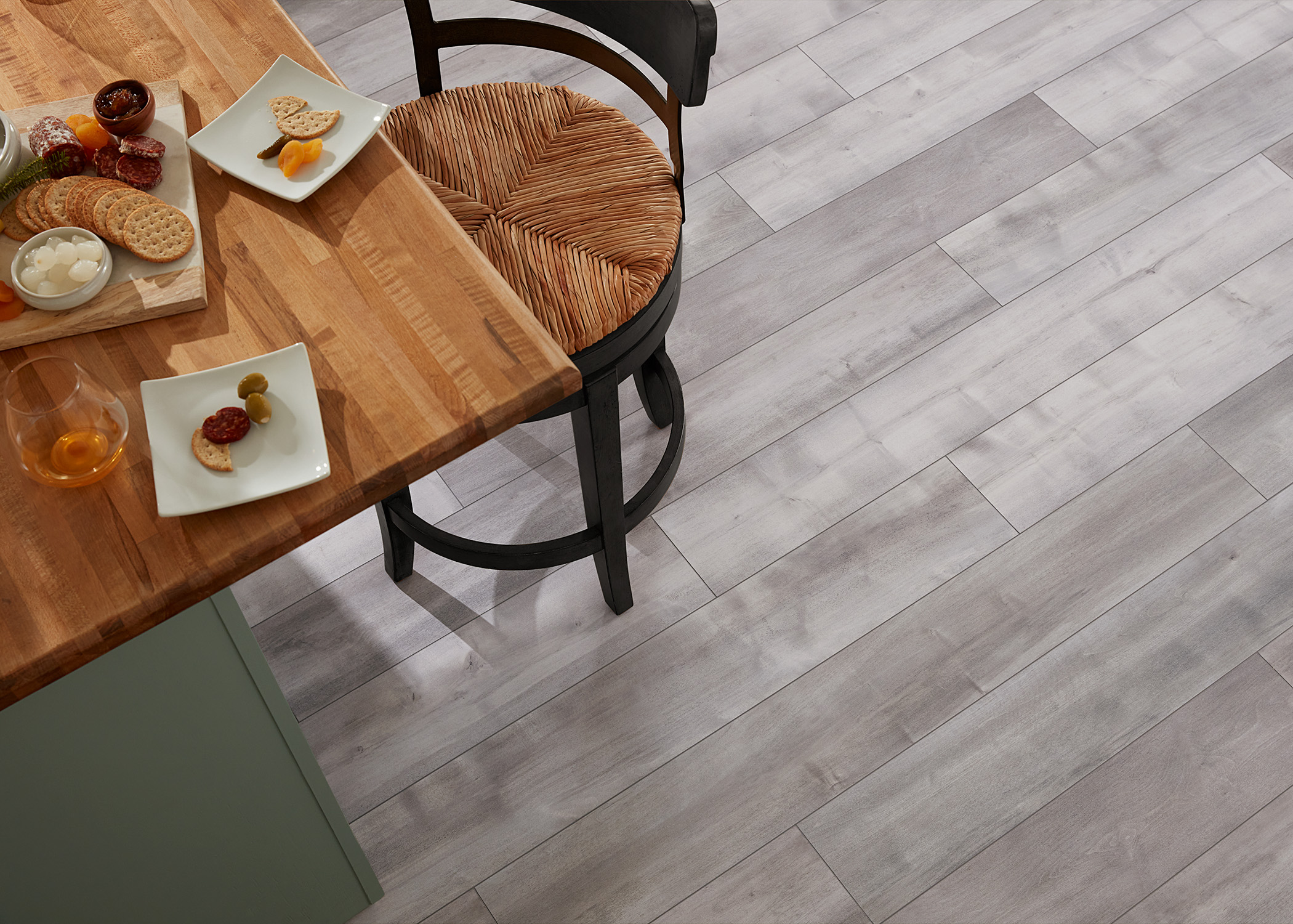 light to medium gray waterproof rigid vinyl plank flooring close up of floor and butcher block island with rattan bar stool