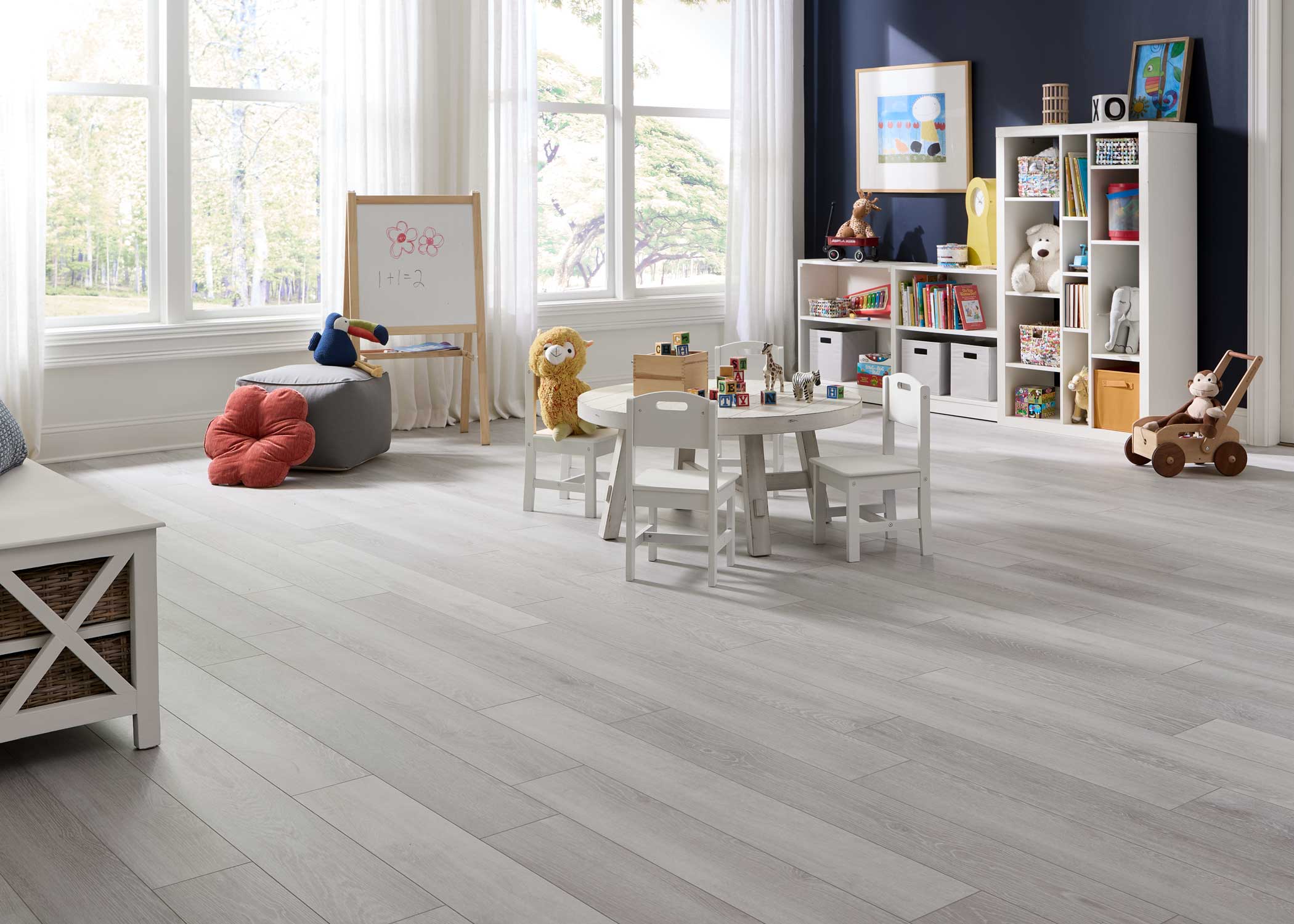 light gray waterproof hybrid resilient flooring in playroom with round white table and chairs plus white bookcase with books and toys plus blonde wood dry erase board