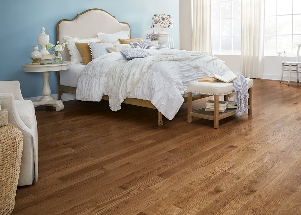 3/4 in. x 3.25 in. Warm Spice Oak Solid Hardwood Flooring in bedroom with pale blue walls and white pucker comforter and beige fabric headboard