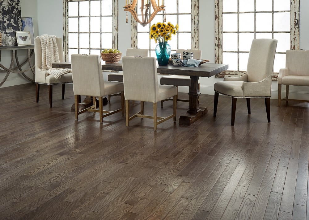 3/4 in. x 3.25 in. Gray Fox Oak Solid Hardwood Flooring in dining room with dark brown dining table and beige upholstered dining chairs plus sunflowers in blue vase on table