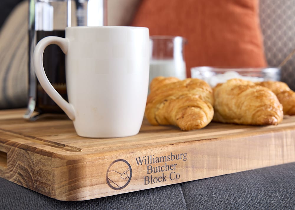 Unfinished Essential Teak 20 in. L x 15 in. W x 1-3/8 in. Th Butcher Block Cutting Board closeup with white coffee mug and croissants