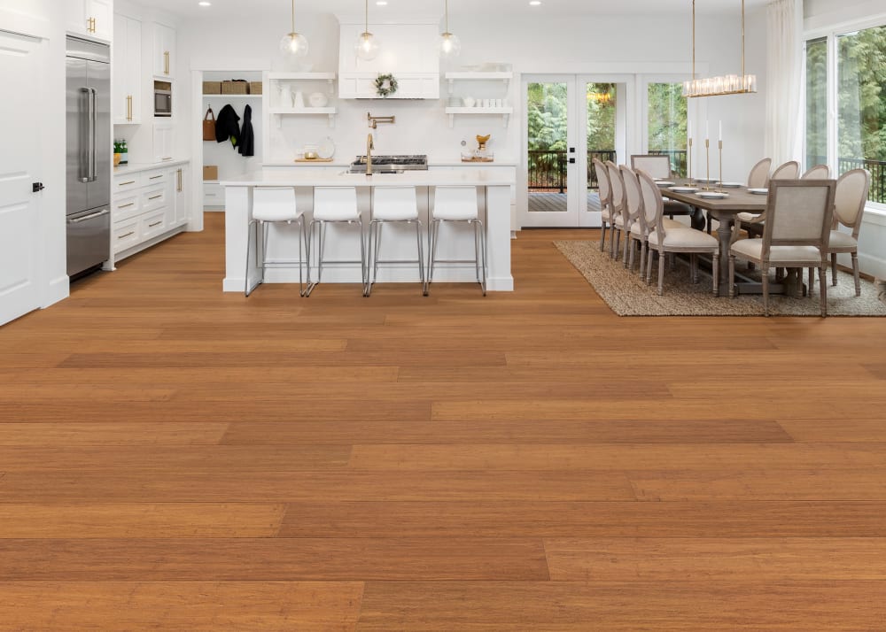 7mm+Pad x 7.5 in Carbonized Strand Water-resistant Engineered Bamboo Flooring in open concept kitchen and dining with white cabinets and island plus medium brown dining table and chairs