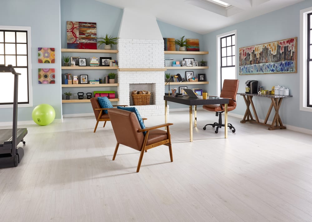 9mm with Pad Urban Mist Oak Waterproof Hybrid Resilient Flooring in office with light blue walls and white brick fireplace plus black and gold desk and dark brown leather chairs