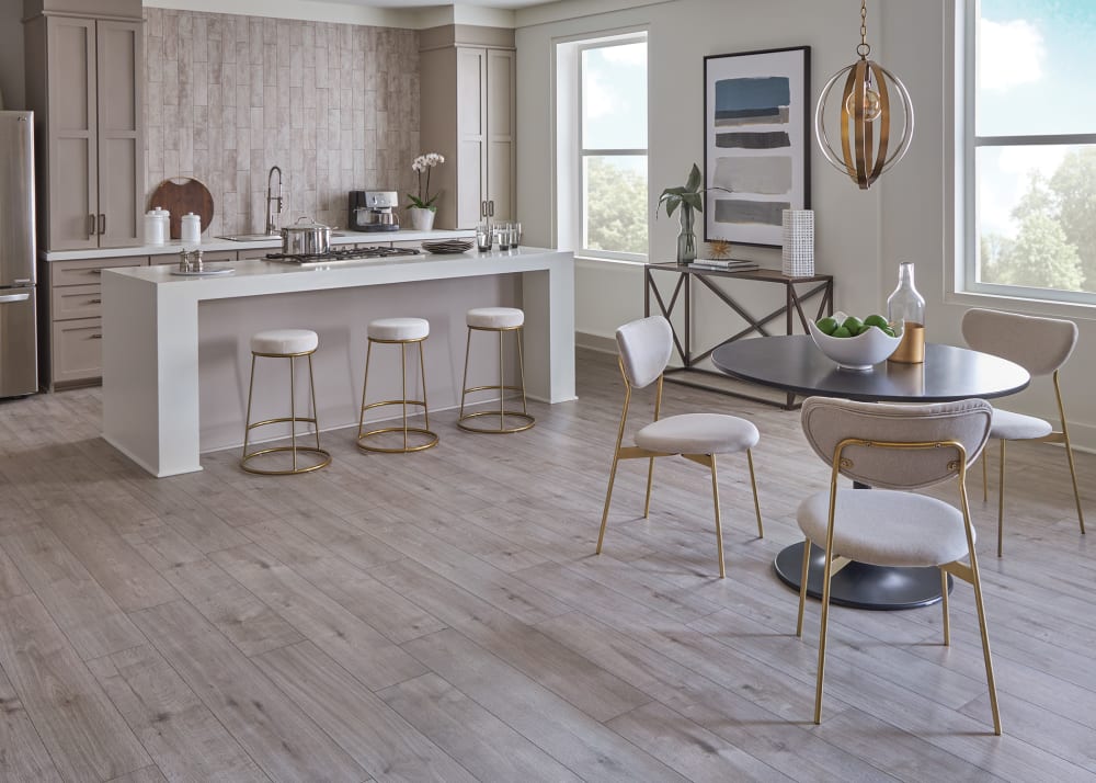 9mm with Pad Gauntlet Gray Oak Hybrid Resilient Flooring in kitchen with large island and gold barstools