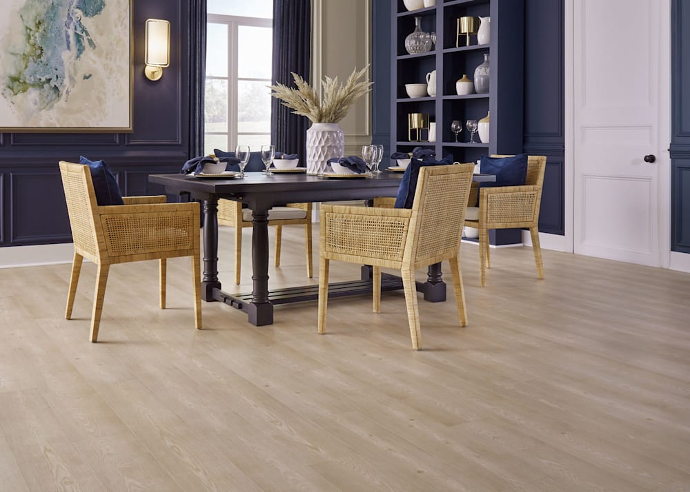 9mm with Pad Mellow Creek Oak Waterproof Hybrid Resilient Flooring in dining room with dark blue walls plus dark brown dining table and blonde wood rattan chairs