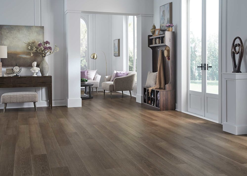 5mm with Pad Woodhill Oak Waterproof Rigid Vinyl Plank Flooring in entryway with double front door coat and storage rack with view into living room with beige furnishings and gold floor lamp