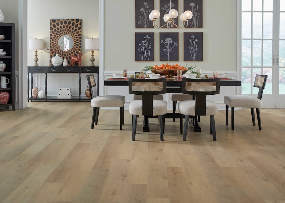 6mm with Pad Shepherd Oak Waterproof Rigid Vinyl Plank Flooring in dining room with dark brown dining table and armless upholstered chairs with cane backing plus black and white artwork and oranges in bowl on table