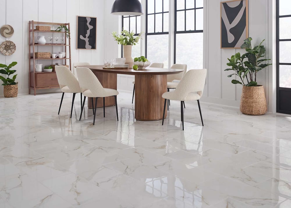 12 in. x 24 in. Marmo Imperiale Stone Look Porcelain Tile Flooring in dining room with medium wood dining table with off white upholstered armless chairs plus black and white abstract artwork and black dome lighting