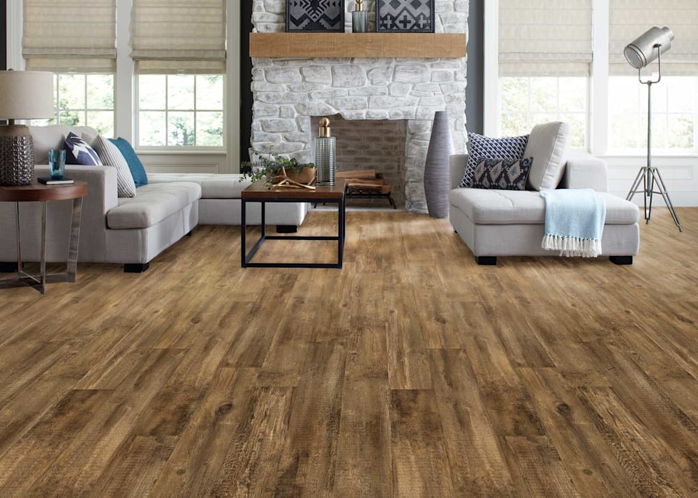 5mm with Pad Rustic Trail Oak Waterproof Rigid Vinyl Plank Flooring in living room with white washed stone fireplace plus beige sectional and dark brown and black coffee table