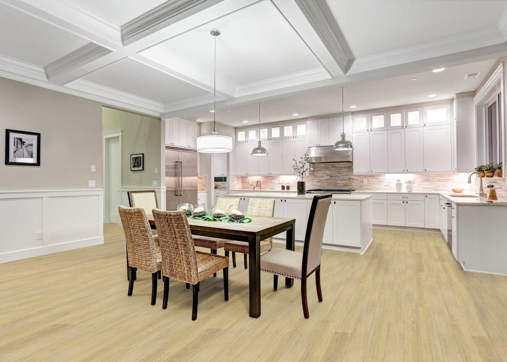 8mm with Pad Clandon Crate Ash Waterproof Rigid Vinyl Plank Flooring in kitchen with white cabinets with cream countertops plus dark wood dining table with rattan chairs and coffered ceiling