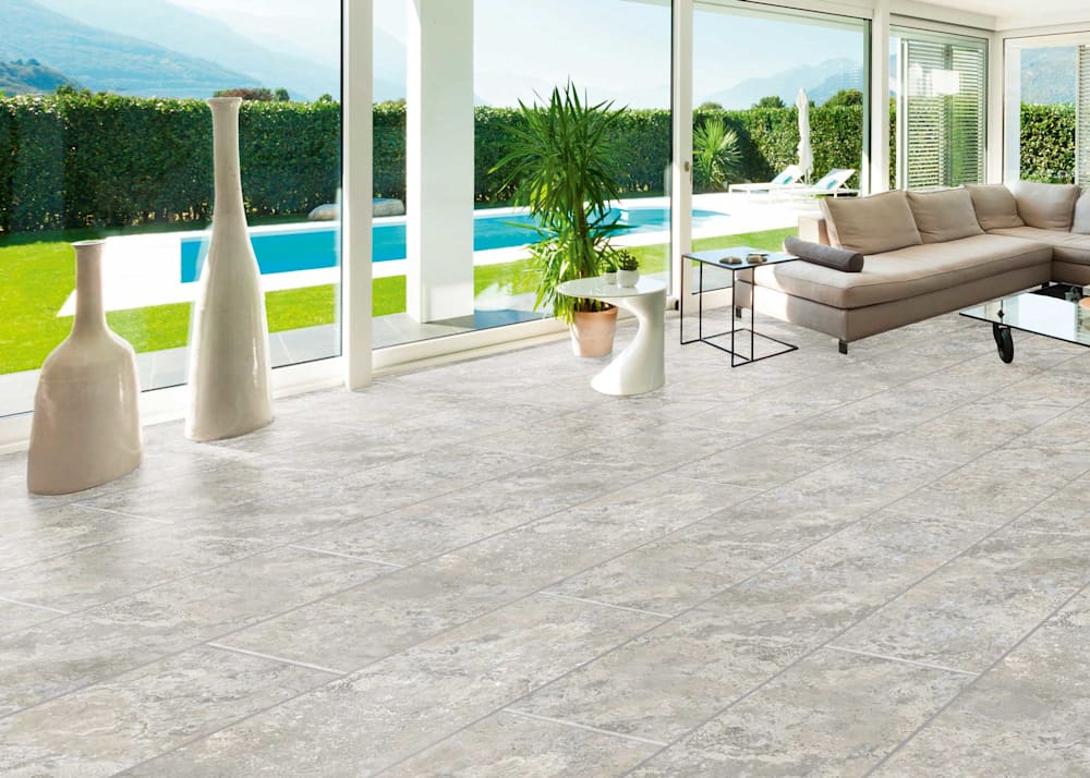 7mm with Pad Antico Travertine Waterproof Rigid Vinyl Tile Flooring in sunroom overlooking inground swimming pool with tan sectional and tall white vases