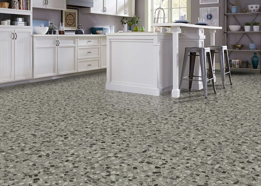 7mm with Pad Grigio Terrazzo Waterproof Rigid Vinyl Tile Flooring in kitchen with white cabinets and countertops plus white island and dark gray metal bar stools