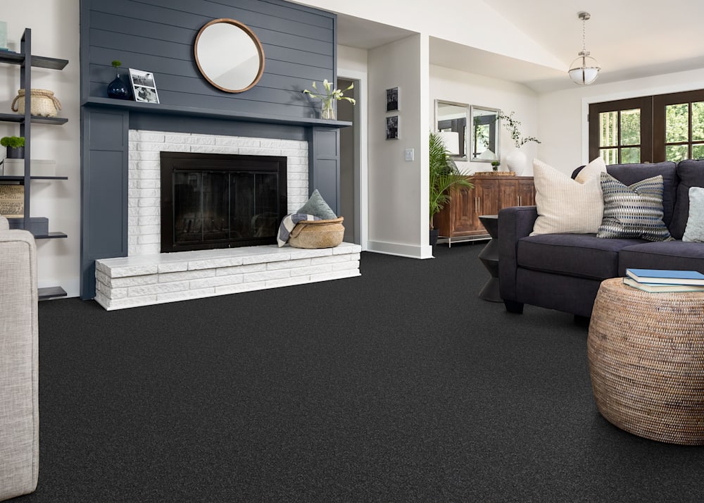 Newcomb Ridge Carpet in Obsidian in living room with dark gray shiplap surrounding fireplace and dark gray upholstered sofa